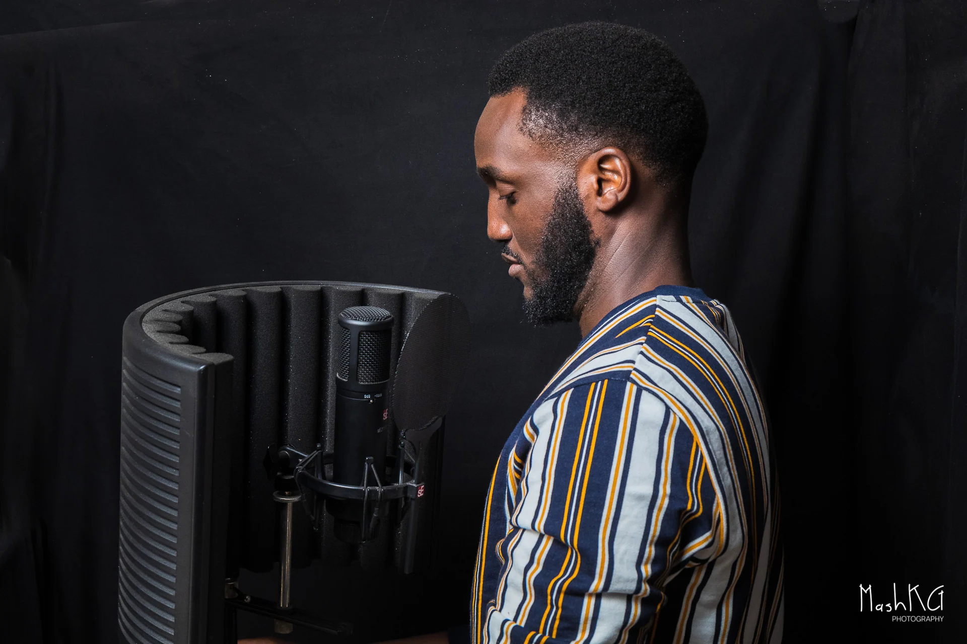 Adrian recording a voice-over behind the microphone in a striped shirt